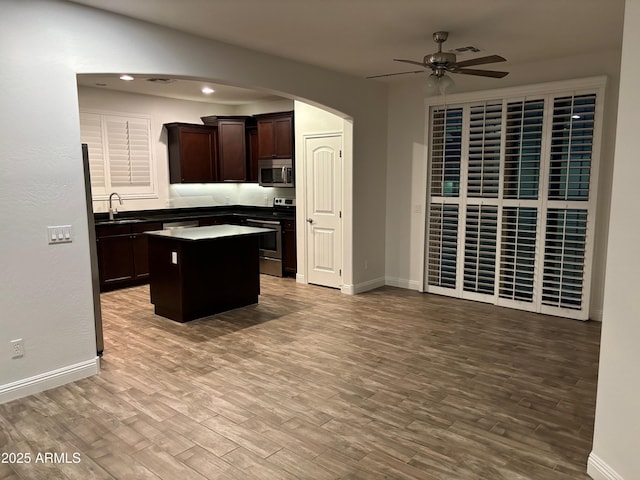 3480 E Sheffield Rd, Gilbert, AZ 85296 - kitchen with stainless steel appliances, ceiling fan, a center island, arched walkways, and dark brown cabinetry