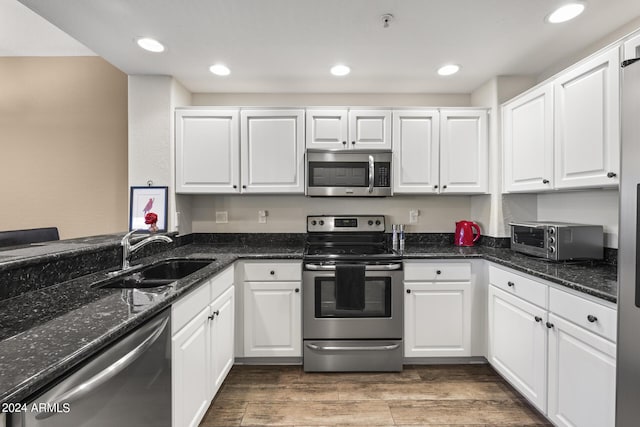 kitchen with sink, stainless steel appliances, dark stone countertops, and white cabinetry