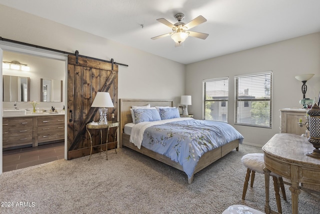 carpeted bedroom with ceiling fan, connected bathroom, a barn door, and sink