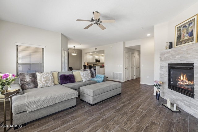 living room featuring a tile fireplace and ceiling fan