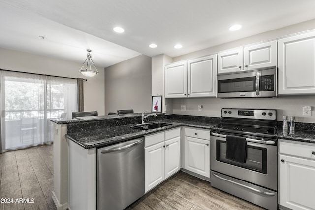 kitchen with kitchen peninsula, appliances with stainless steel finishes, and white cabinetry