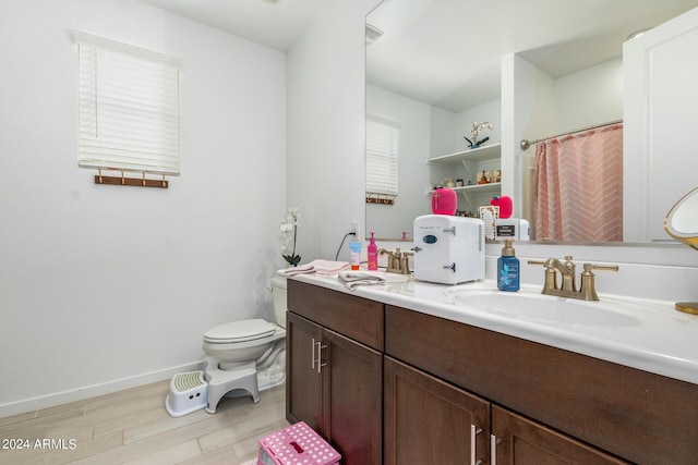 bathroom with wood-type flooring, vanity, toilet, and plenty of natural light