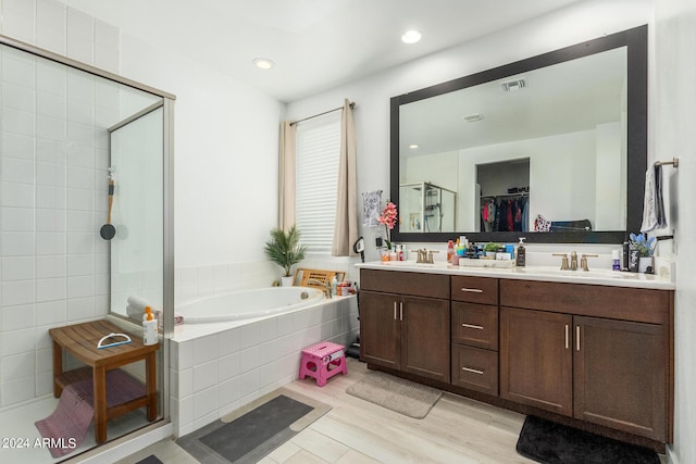 bathroom featuring plus walk in shower, vanity, and hardwood / wood-style flooring