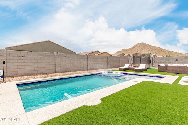 view of pool featuring a mountain view, a trampoline, an outdoor hangout area, a yard, and an in ground hot tub