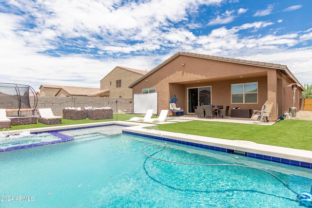 view of swimming pool featuring a lawn, a patio area, a trampoline, and an in ground hot tub