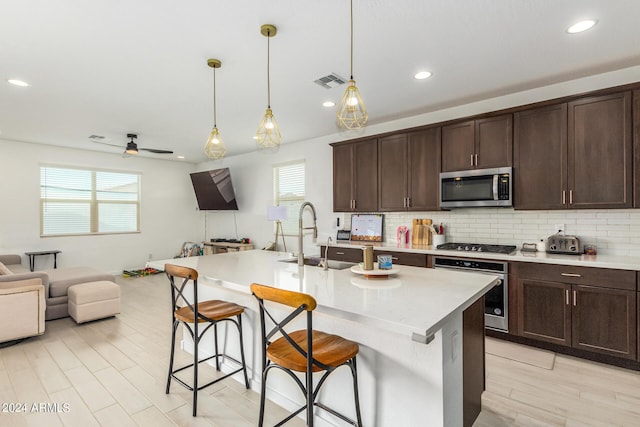 kitchen featuring pendant lighting, a center island with sink, sink, a breakfast bar area, and stainless steel appliances