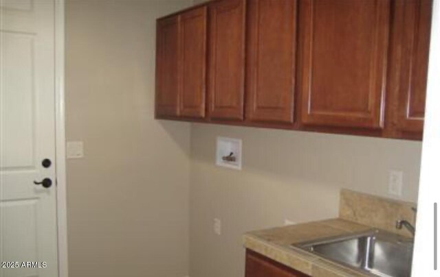 laundry area with cabinet space, hookup for a washing machine, and a sink