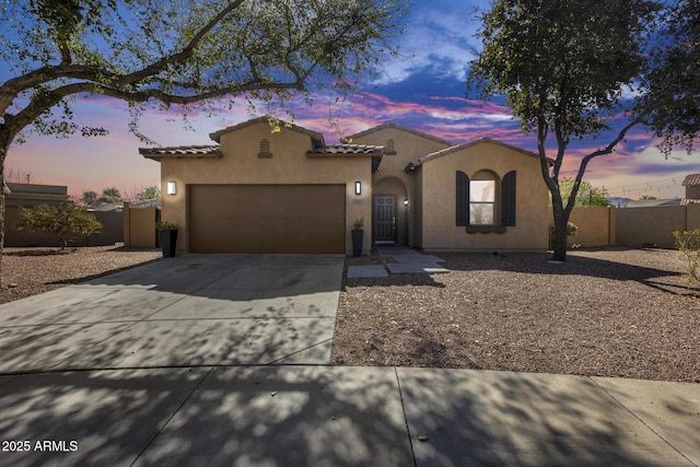 mediterranean / spanish home featuring fence, an attached garage, stucco siding, concrete driveway, and a tile roof