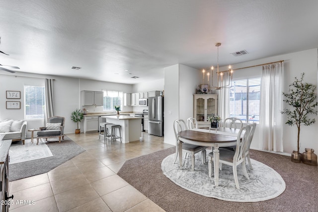 dining area with a notable chandelier, visible vents, light tile patterned floors, and plenty of natural light