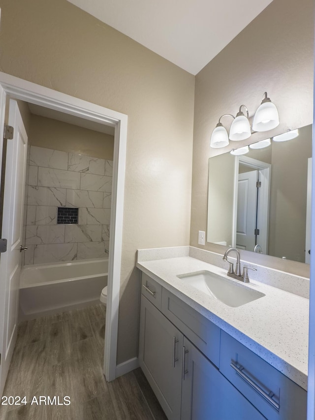 full bathroom featuring tiled shower / bath, vanity, wood-type flooring, and toilet