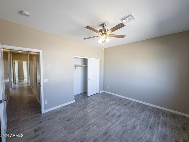 unfurnished bedroom with ceiling fan, a closet, and dark hardwood / wood-style floors