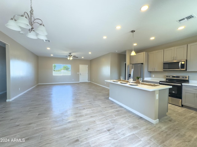 kitchen with appliances with stainless steel finishes, ceiling fan with notable chandelier, decorative light fixtures, gray cabinets, and an island with sink