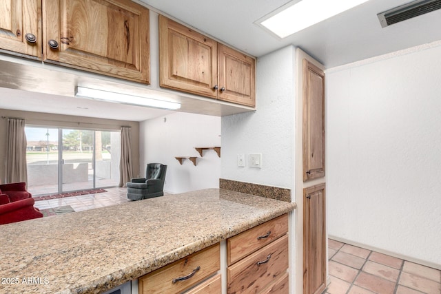 kitchen featuring light tile patterned flooring and light stone counters