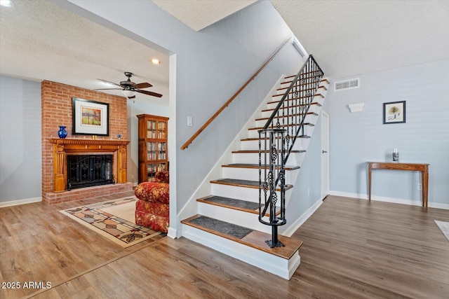 8545 E Heatherbrae Dr, Scottsdale, AZ 85251 - staircase with wood finished floors, a ceiling fan, a brick fireplace, a textured ceiling, and recessed lighting