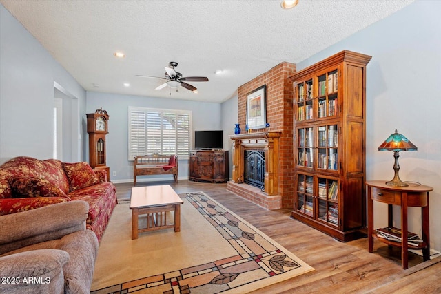 8545 E Heatherbrae Dr, Scottsdale, AZ 85251 - living room featuring a brick fireplace, wood finished floors, a ceiling fan, recessed lighting, and a textured ceiling