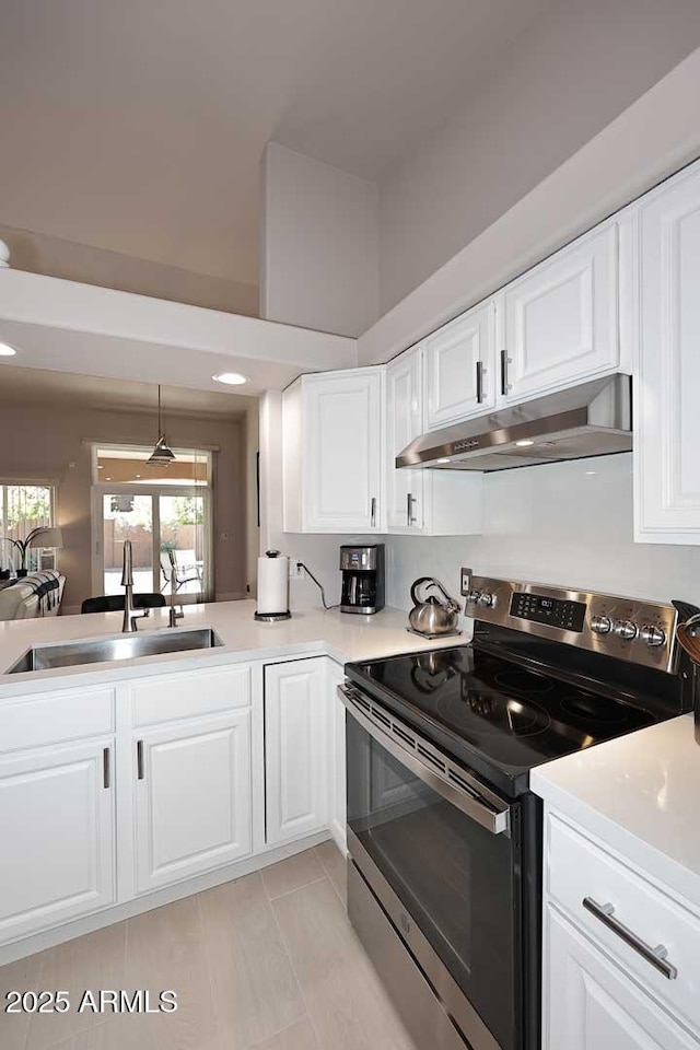 kitchen featuring under cabinet range hood, white cabinetry, stainless steel range with electric stovetop, and a sink