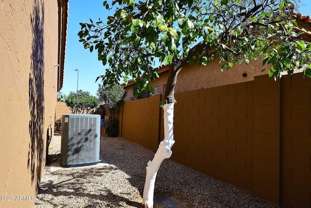 view of property exterior featuring central AC unit and fence