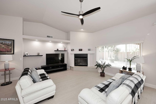 living room with visible vents, baseboards, vaulted ceiling, a glass covered fireplace, and a ceiling fan