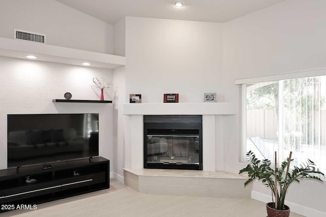 living room featuring visible vents, baseboards, and a glass covered fireplace