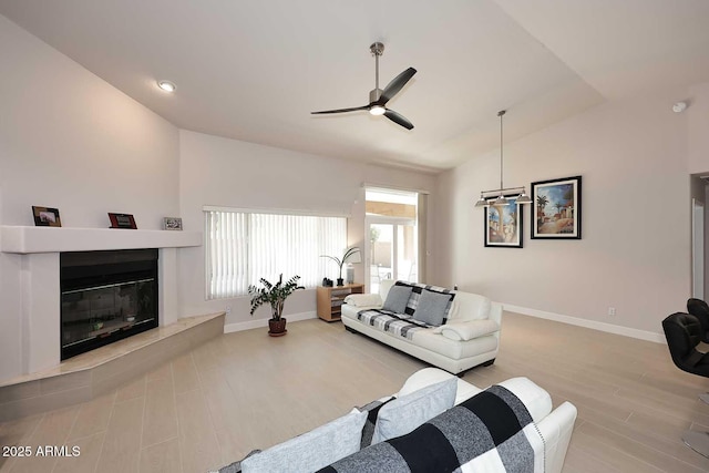 living room featuring a glass covered fireplace, vaulted ceiling, wood finished floors, and a ceiling fan