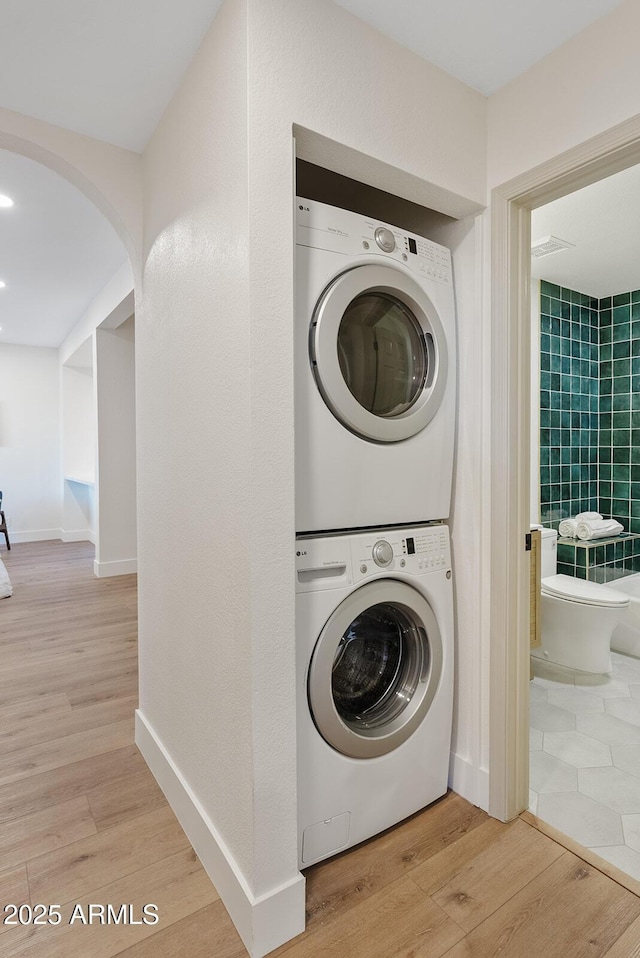 9708 E Via Linda Rd Unit 1350, Scottsdale, AZ 85258 - laundry area featuring stacked washer / dryer, light wood-style floors, and arched walkways