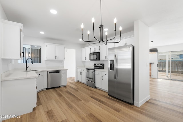 kitchen with white cabinetry, hanging light fixtures, and appliances with stainless steel finishes