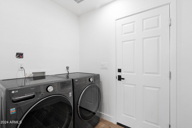 clothes washing area with hardwood / wood-style flooring and independent washer and dryer