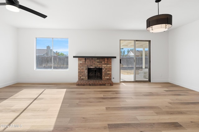 unfurnished living room with a fireplace, plenty of natural light, light hardwood / wood-style flooring, and ceiling fan