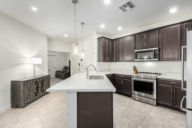 kitchen featuring decorative light fixtures, appliances with stainless steel finishes, dark brown cabinetry, and sink