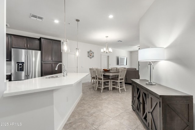 kitchen featuring pendant lighting, sink, ceiling fan with notable chandelier, high end fridge, and dark brown cabinetry