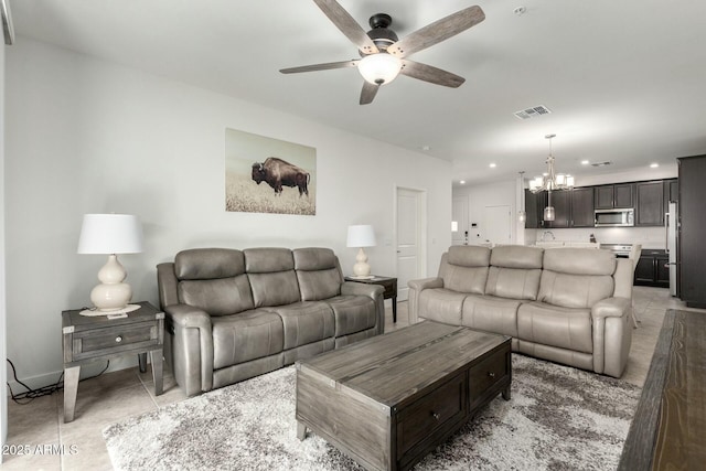 living room with sink, light tile patterned flooring, and ceiling fan with notable chandelier