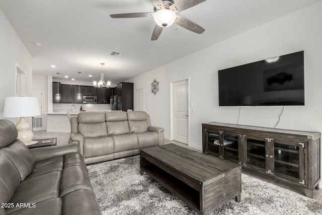 living room with sink and ceiling fan with notable chandelier