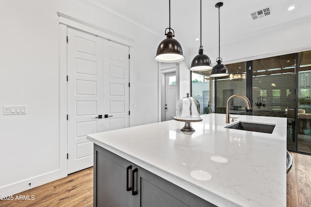 306 W Culver St, Phoenix, AZ 85003 - kitchen featuring a sink, ornamental molding, light wood-style flooring, hanging light fixtures, and light stone countertops