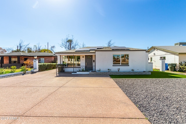 ranch-style home with solar panels and a porch