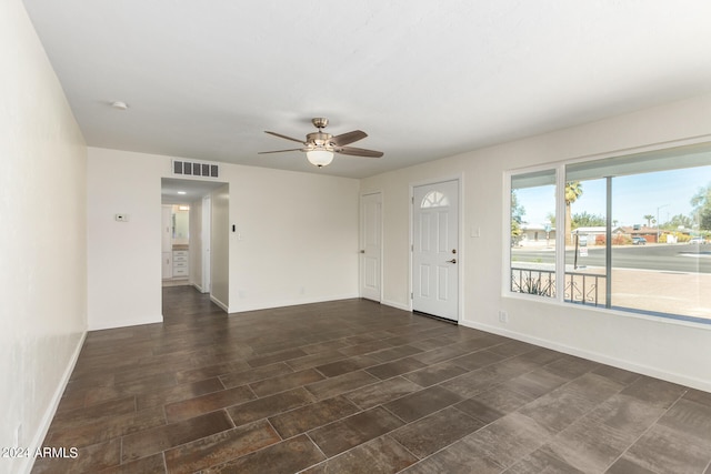 foyer entrance featuring ceiling fan and dark tile flooring