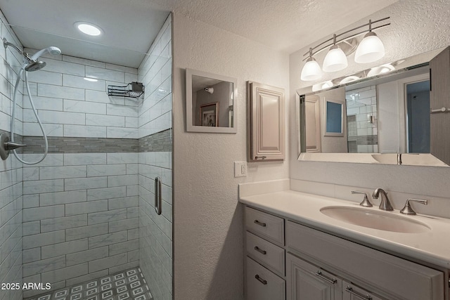 bathroom featuring a shower with shower door, vanity, and a textured ceiling