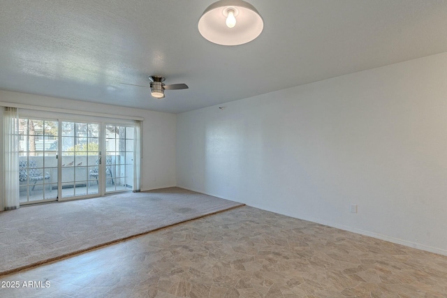 empty room with ceiling fan, light carpet, and a textured ceiling