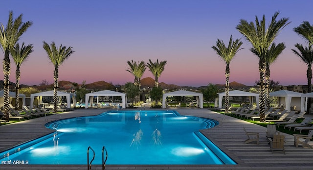 pool at dusk with a community pool and a gazebo