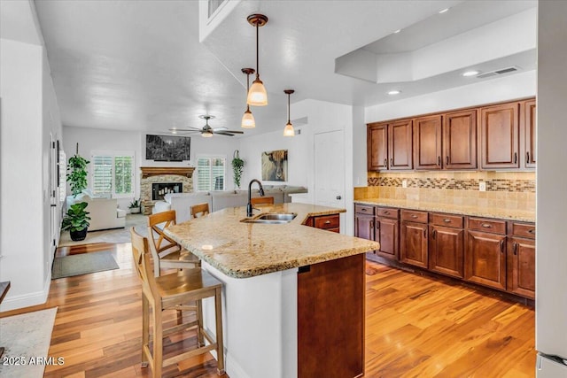 4402 E Barwick Dr, Cave Creek, AZ 85331 - kitchen featuring light wood-style floors, ceiling fan, tasteful backsplash, a stone fireplace, and pendant lighting