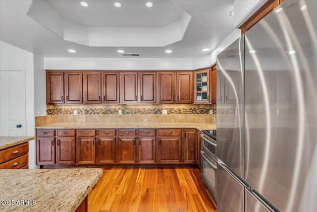 4402 E Barwick Dr, Cave Creek, AZ 85331 - kitchen with freestanding refrigerator, a tray ceiling, light wood-style floors, brown cabinetry, and recessed lighting