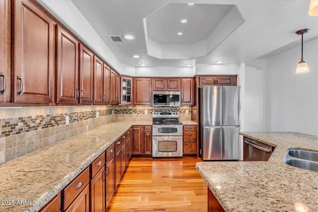 4402 E Barwick Dr, Cave Creek, AZ 85331 - kitchen with appliances with stainless steel finishes, light wood finished floors, a raised ceiling, hanging light fixtures, and glass insert cabinets