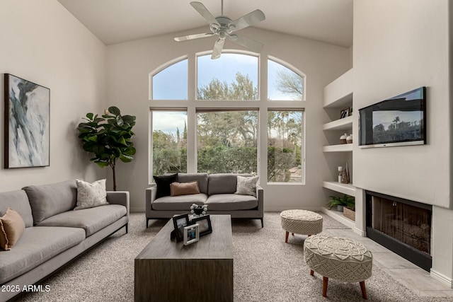 carpeted living room with built in shelves, ceiling fan, and plenty of natural light