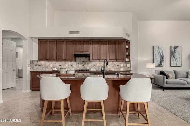 kitchen with a center island with sink, a towering ceiling, sink, and a breakfast bar area