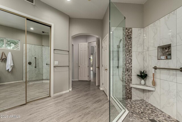 bathroom with tiled shower and hardwood / wood-style floors