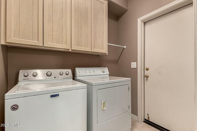 clothes washing area with cabinets and washing machine and clothes dryer