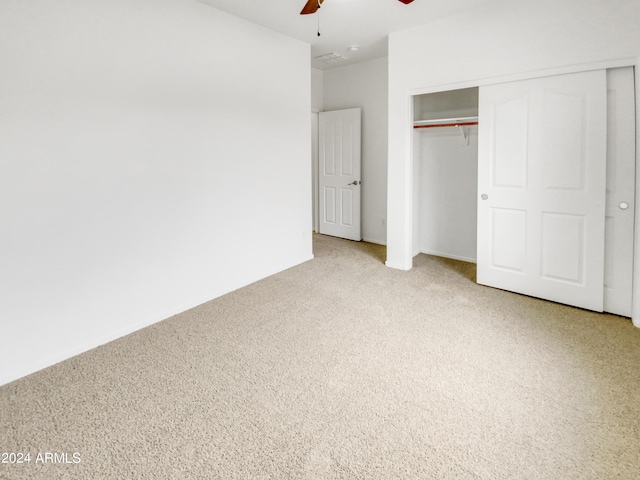 unfurnished bedroom featuring a closet, ceiling fan, and light colored carpet