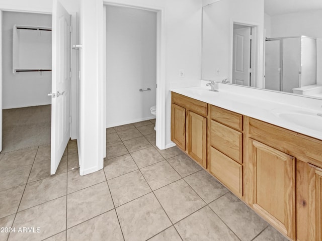 bathroom with tile patterned floors, vanity, toilet, and a shower with shower door