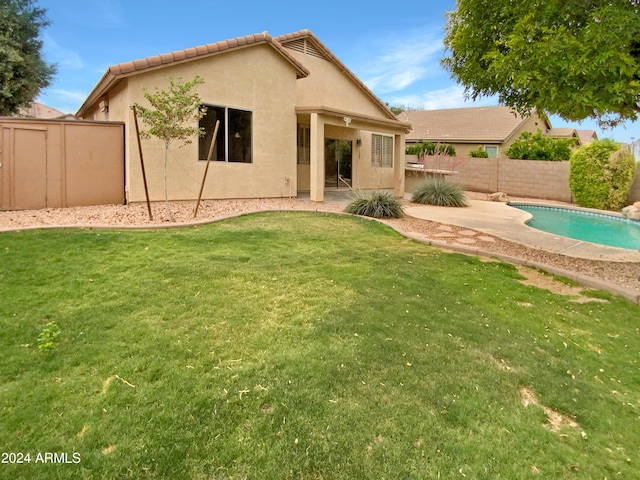 back of house with a patio, a fenced in pool, and a lawn