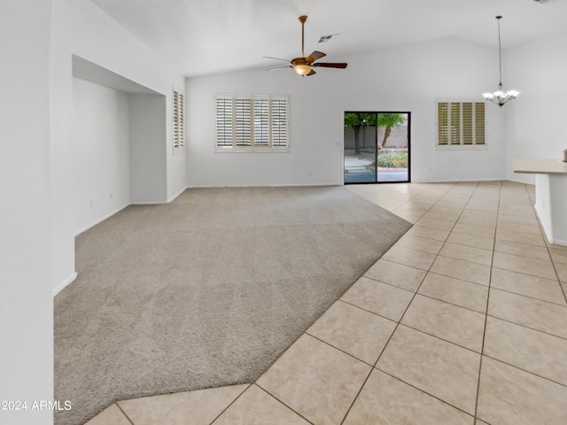 unfurnished living room with ceiling fan with notable chandelier, light colored carpet, and vaulted ceiling