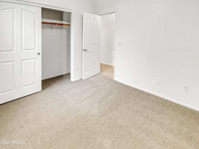 unfurnished bedroom featuring light carpet and a closet